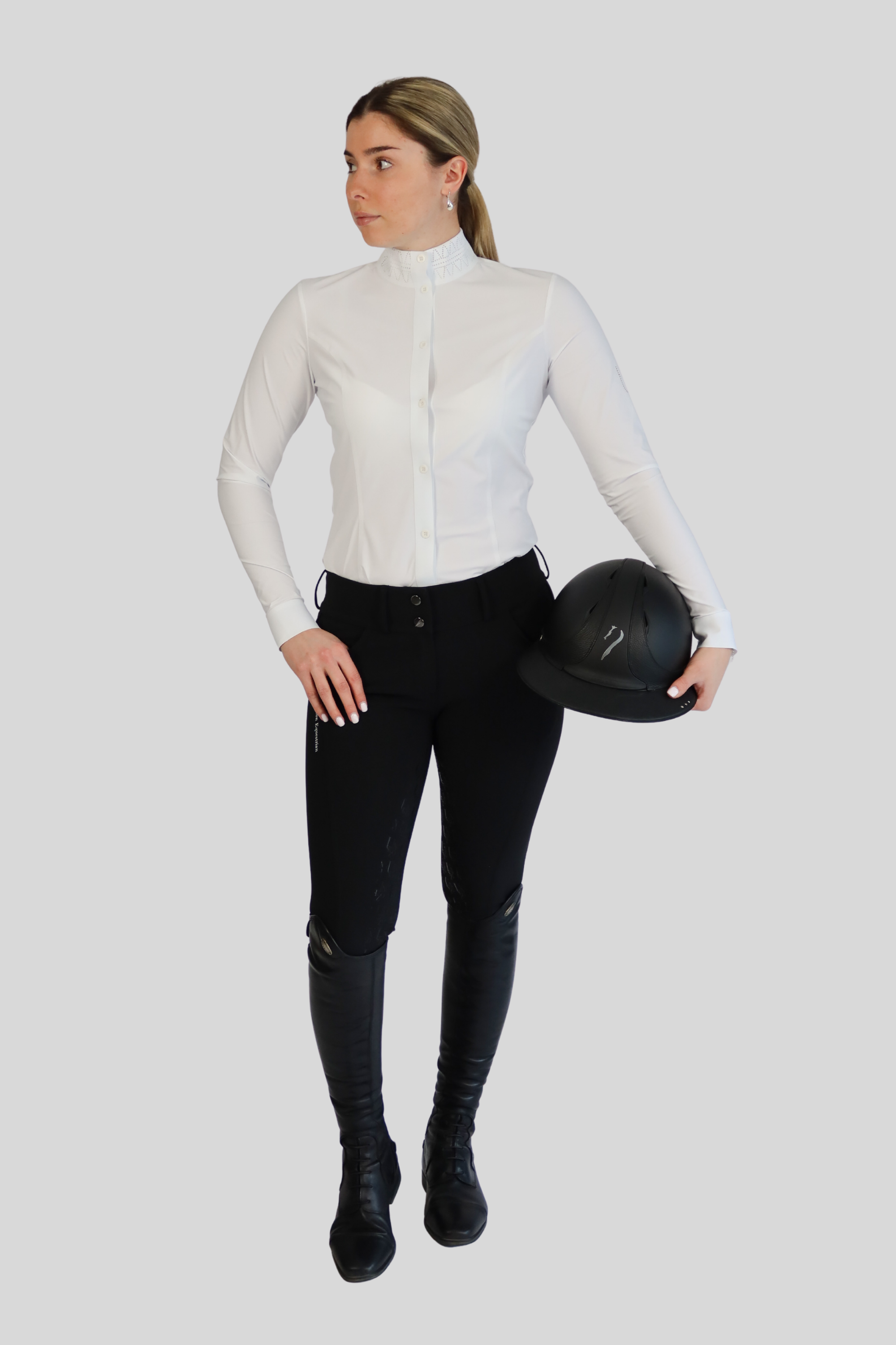Woman in equestrian attire holding a helmet on a white background