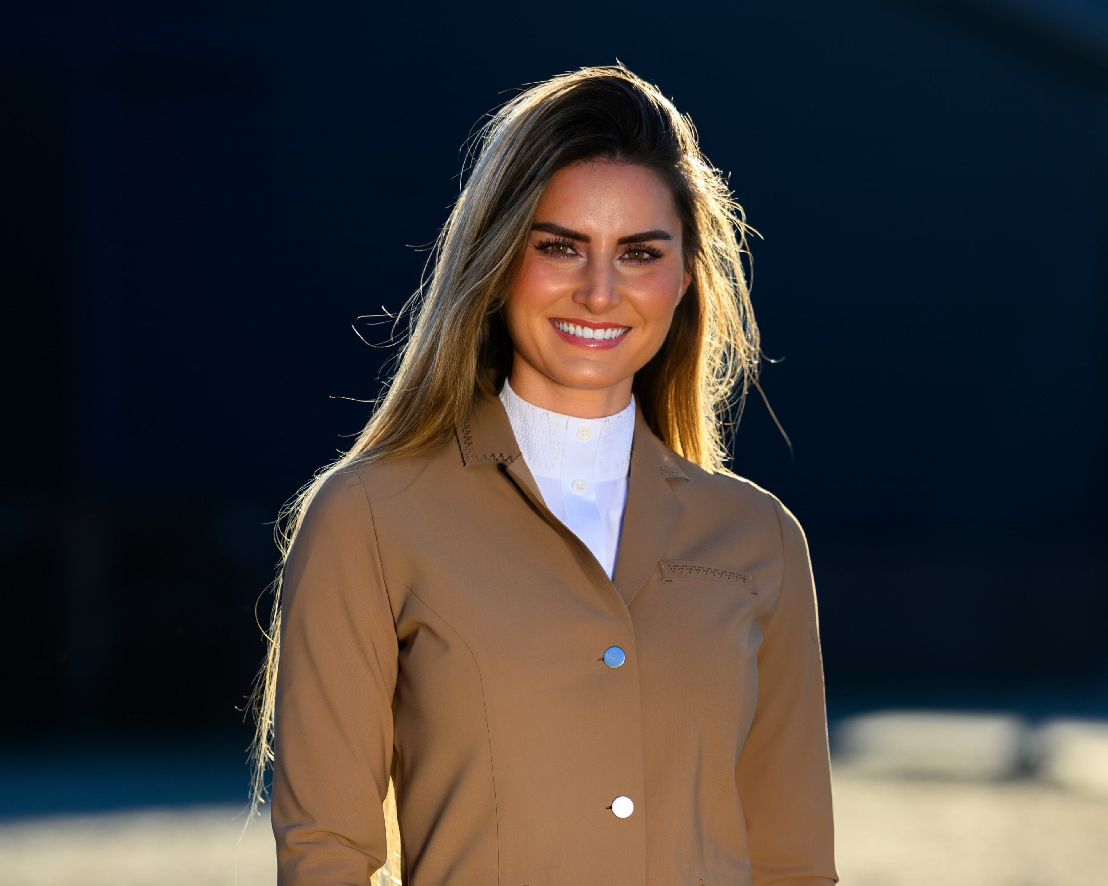 Woman wearing a brown equestrian jacket and white pants .